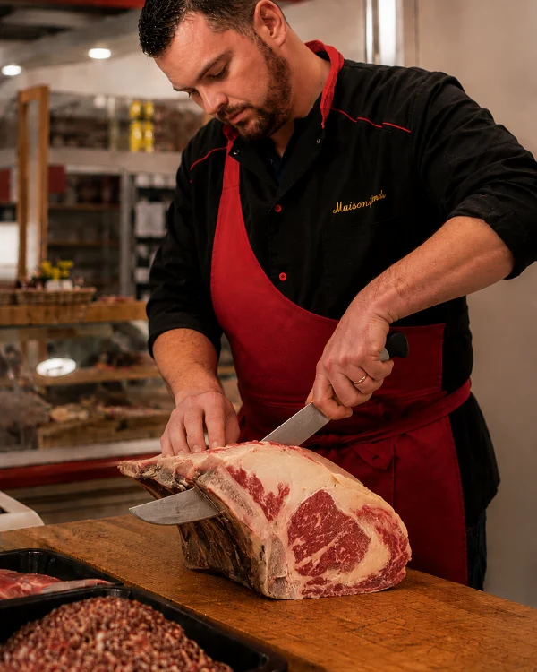 Un boucher détaille une côte de bœuf sur le billot