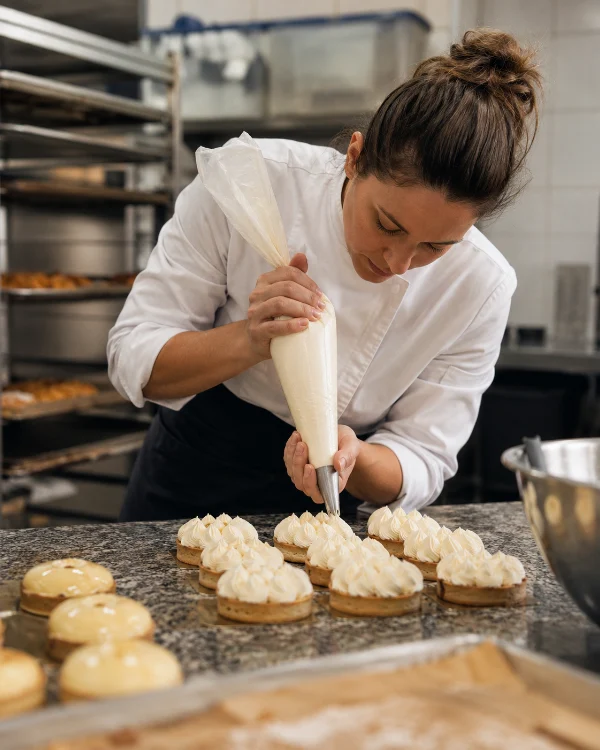 Une pâtissière dresse des tartelettes à la poche